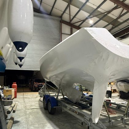 Small boat on a trailer wrapped tight in white shrink wrap