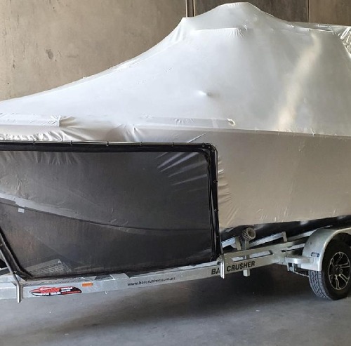 Shrink wrapped cruiser on a trailer with a clear access panel